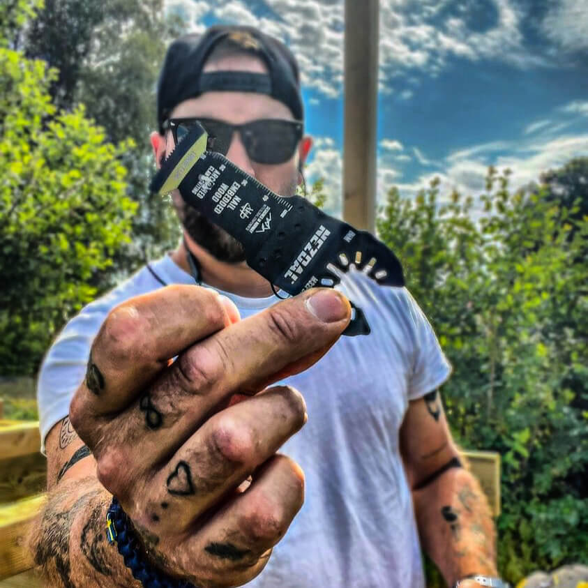 carpenter holding a oscillating multi-tool blade in his hand