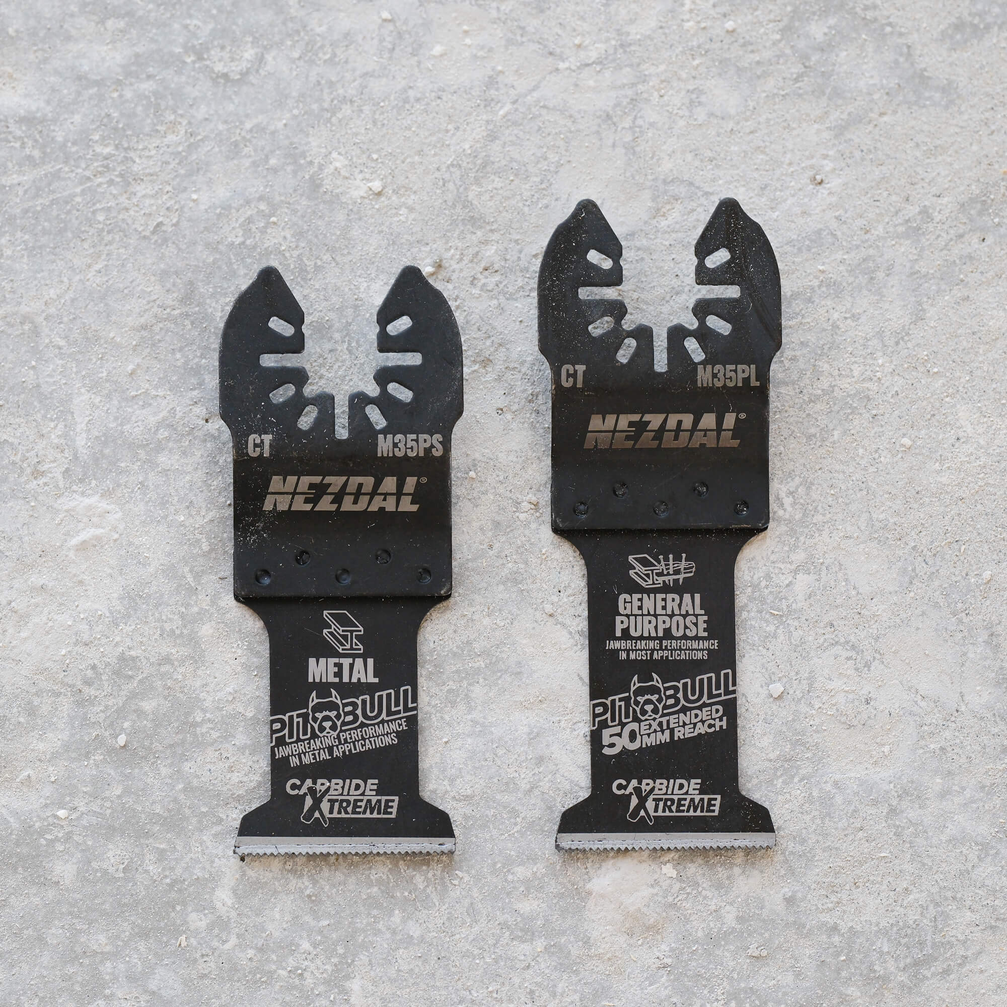 Two multi-tool blades laying besides eachother on concrete